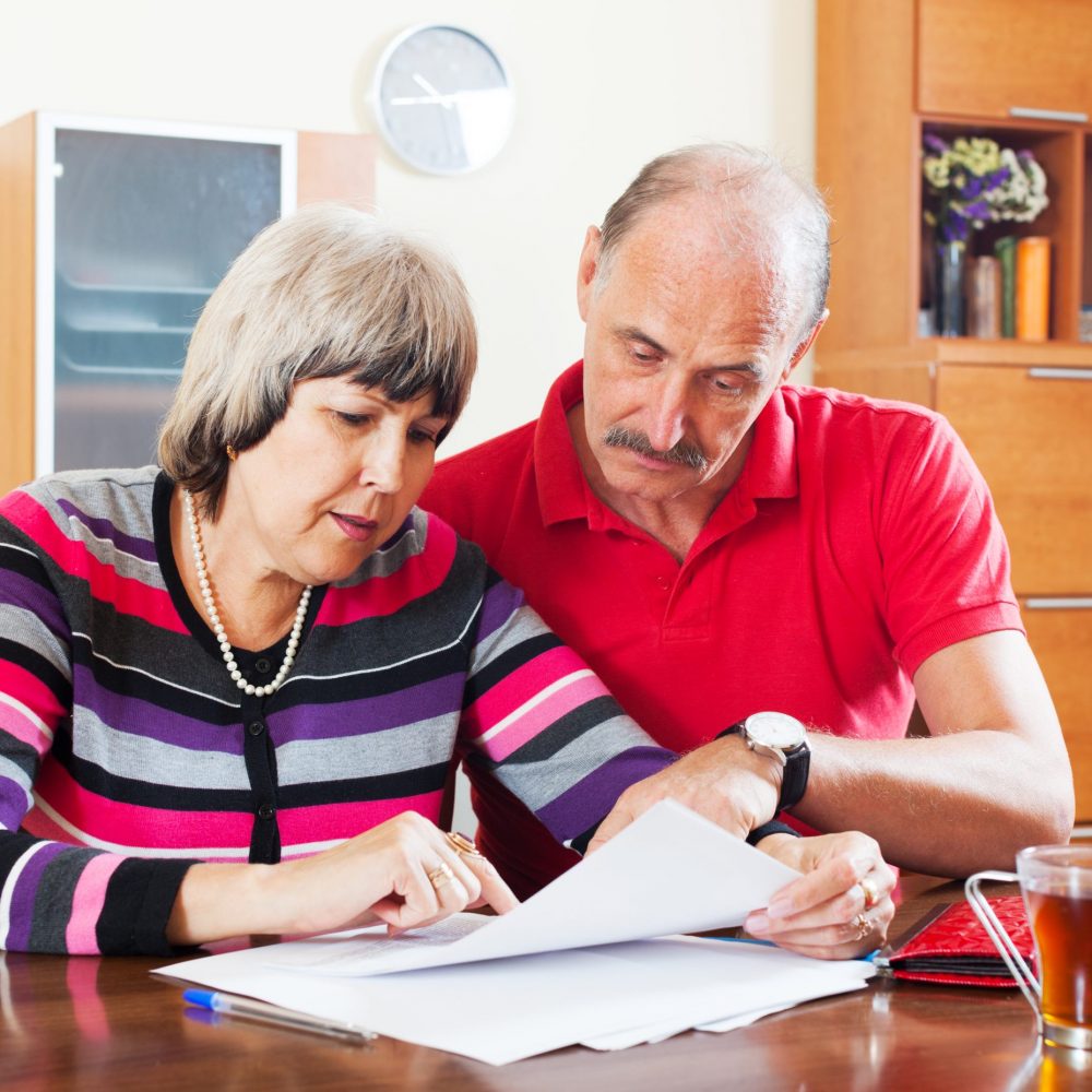 serious mature couple reading financial document together